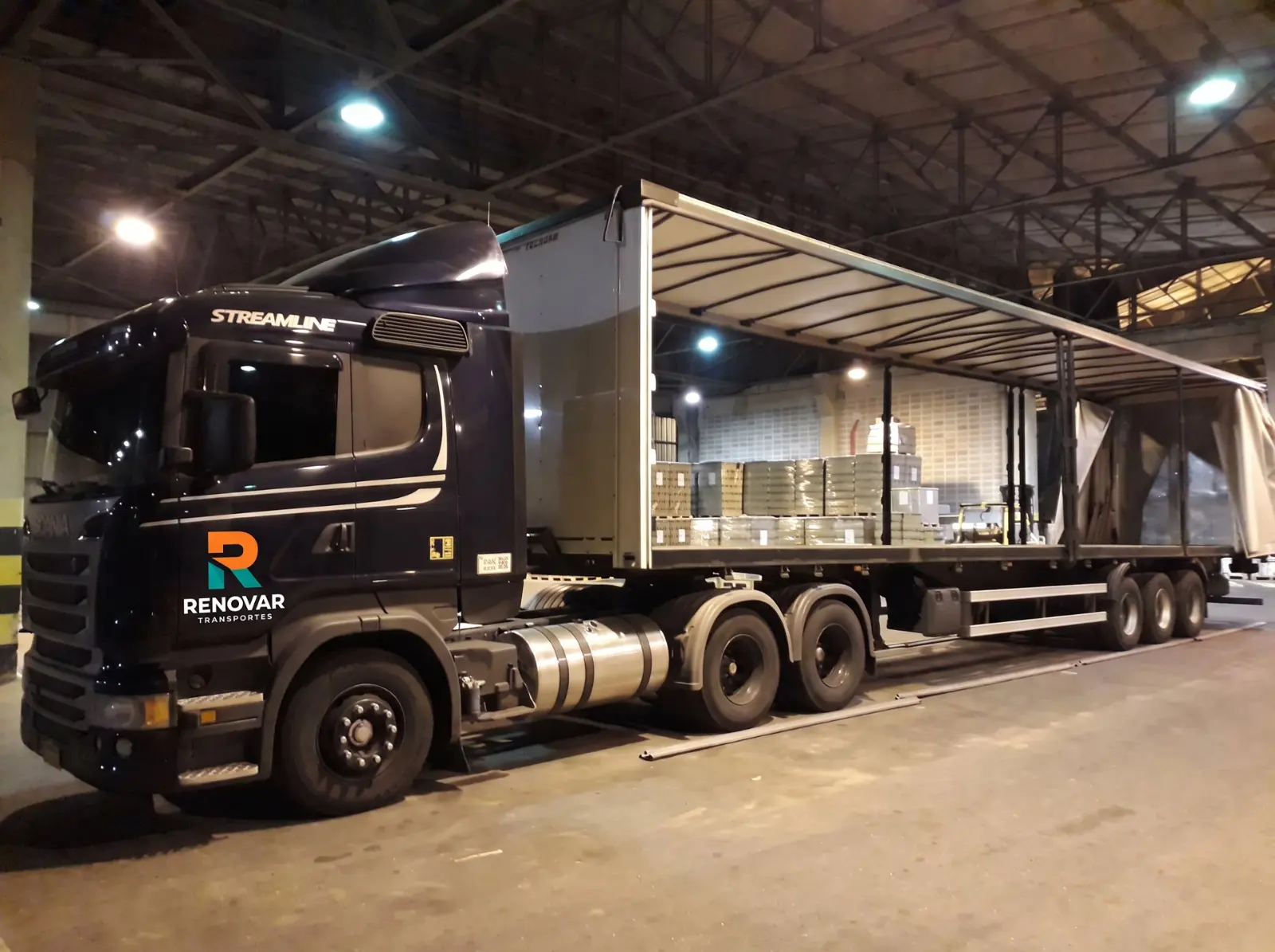 Scania da Renovar com sider aberto sendo carregada no galpão